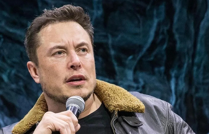 Elon Musk talking and holding a microphone