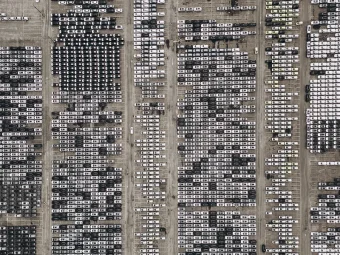An aerial view of cars parked at a dock waiting to be driven on a shipping vessel
