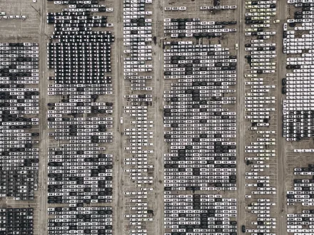 An aerial view of cars parked at a dock waiting to be driven on a shipping vessel